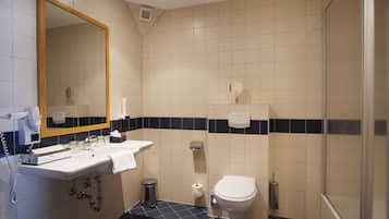 A bathroom with a sink, mirror, toilet, and shower.