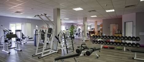 Ett gym med olika typer av träningsutrustning, inklusive hantlar och styrketräningsmaskiner.