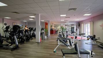 Un gimnasio con máquinas de cardio, zonas de pesas y una recepción.