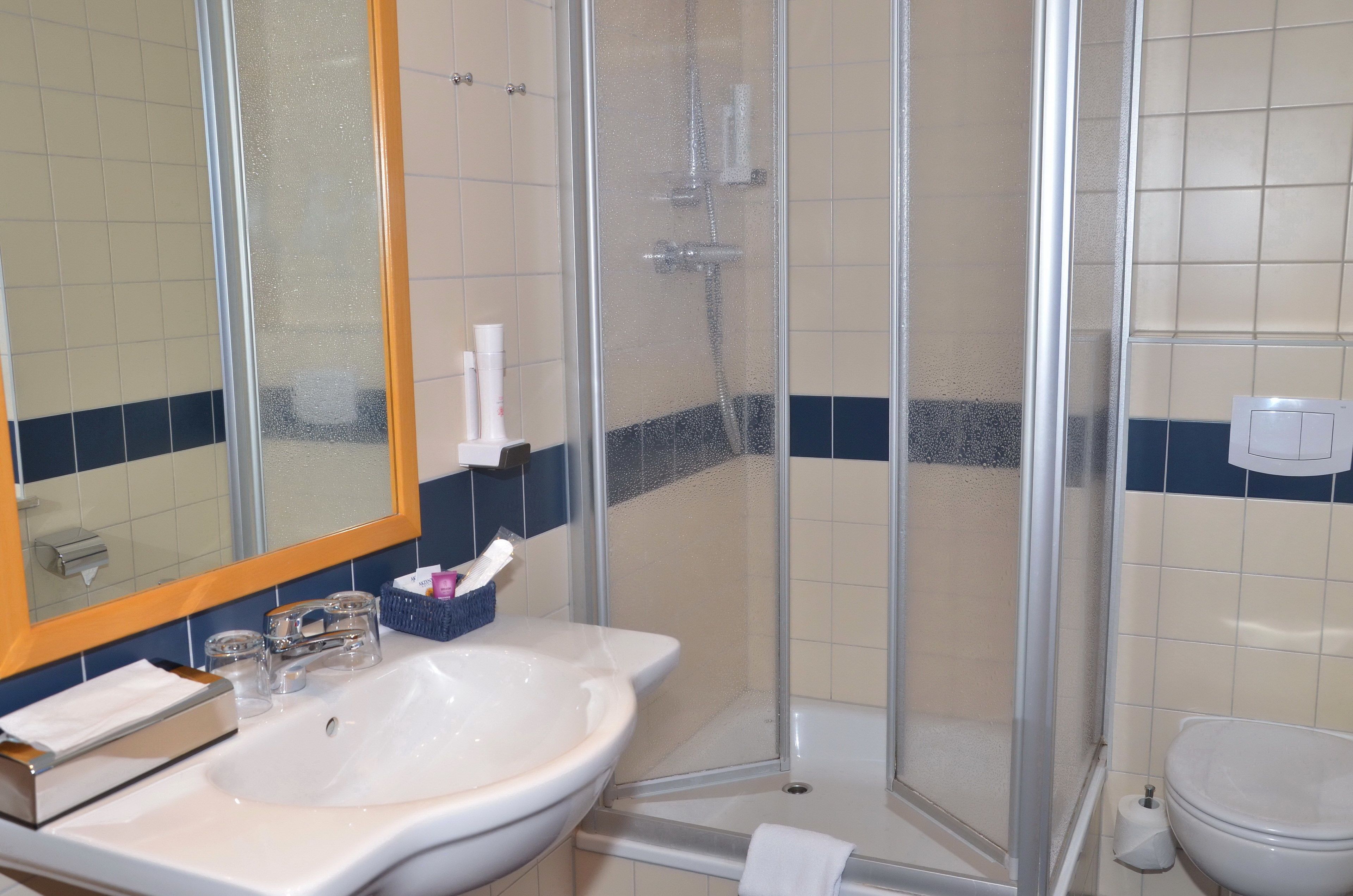 A bathroom with a glass-enclosed shower, a sink, and a toilet.