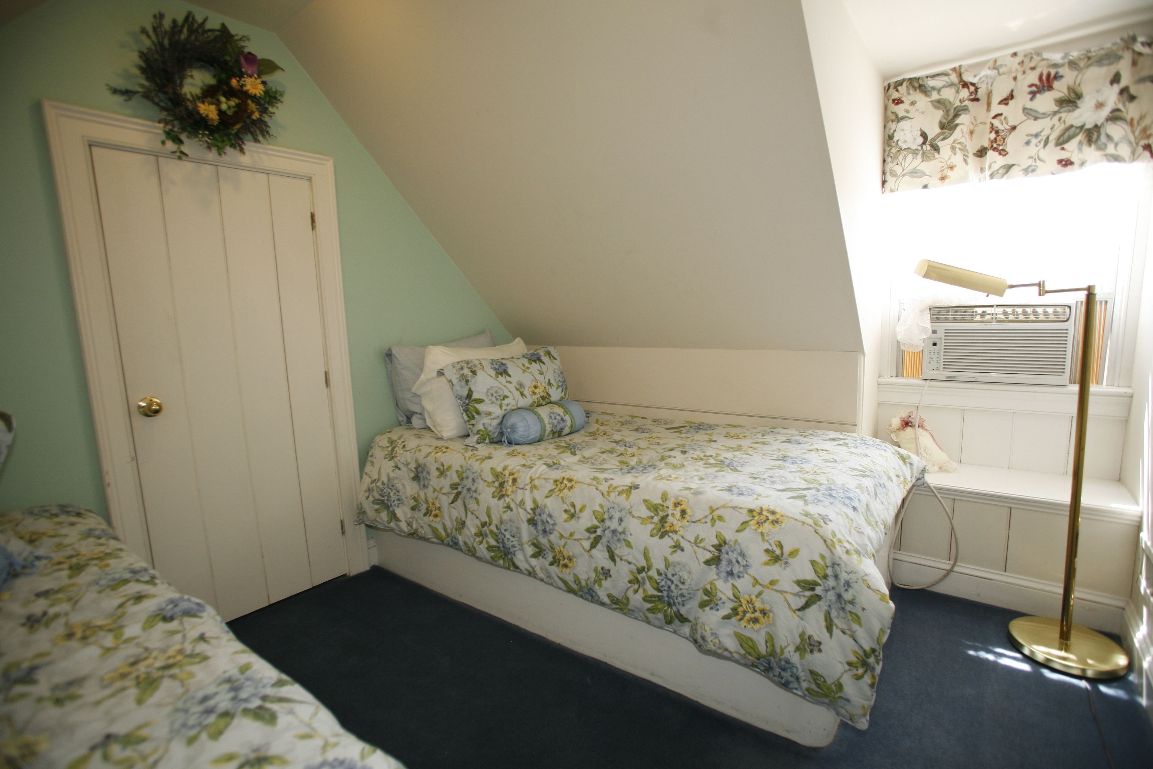 Un dormitorio con cama, cómoda, radiador y ventana con cortina floral.