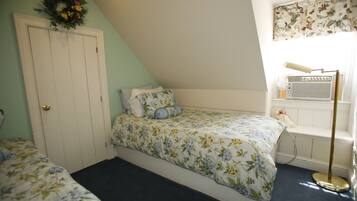 Un dormitorio con cama, cómoda, radiador y ventana con cortina floral.