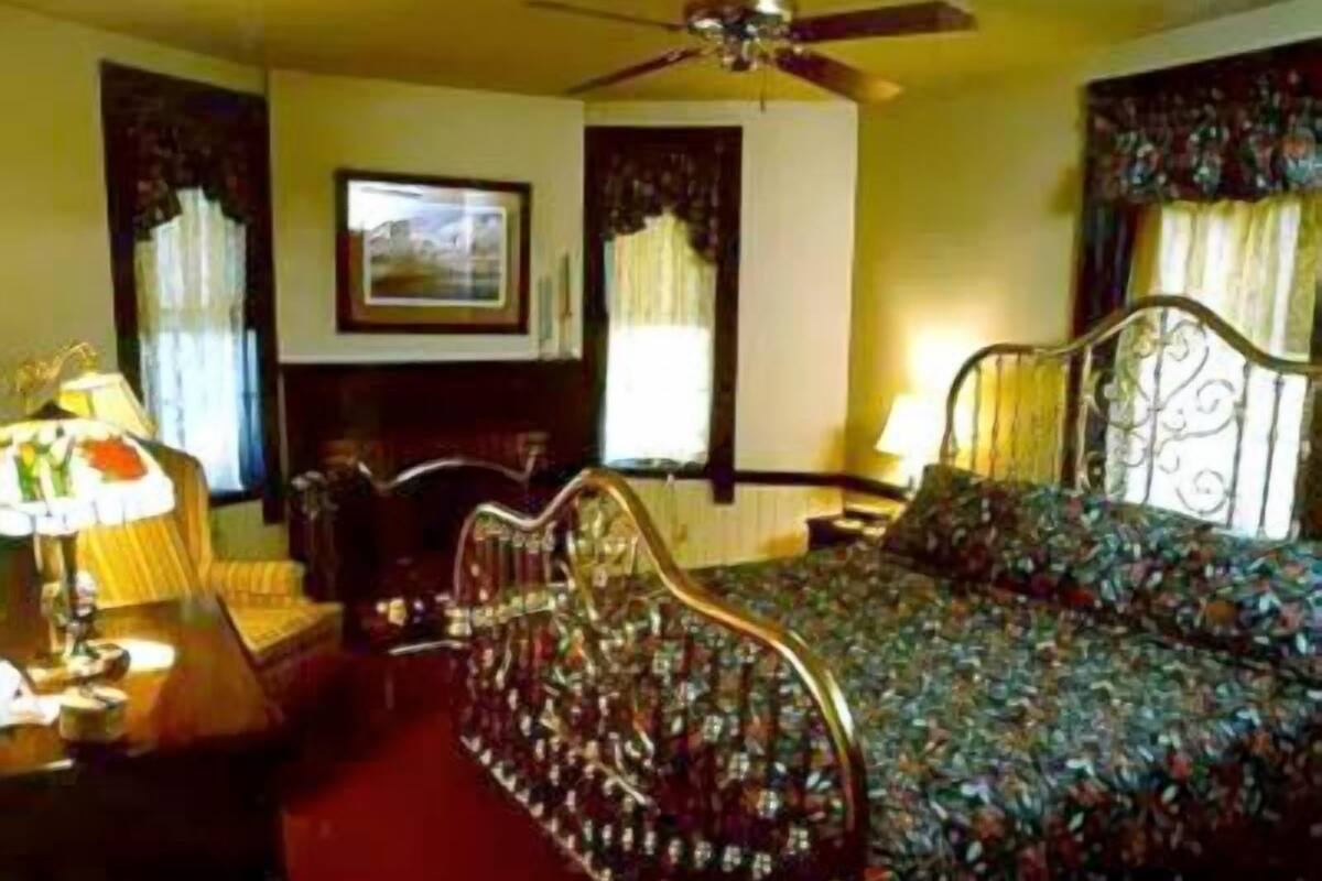 A bedroom with a bed, a chair, a desk, and a ceiling fan.
