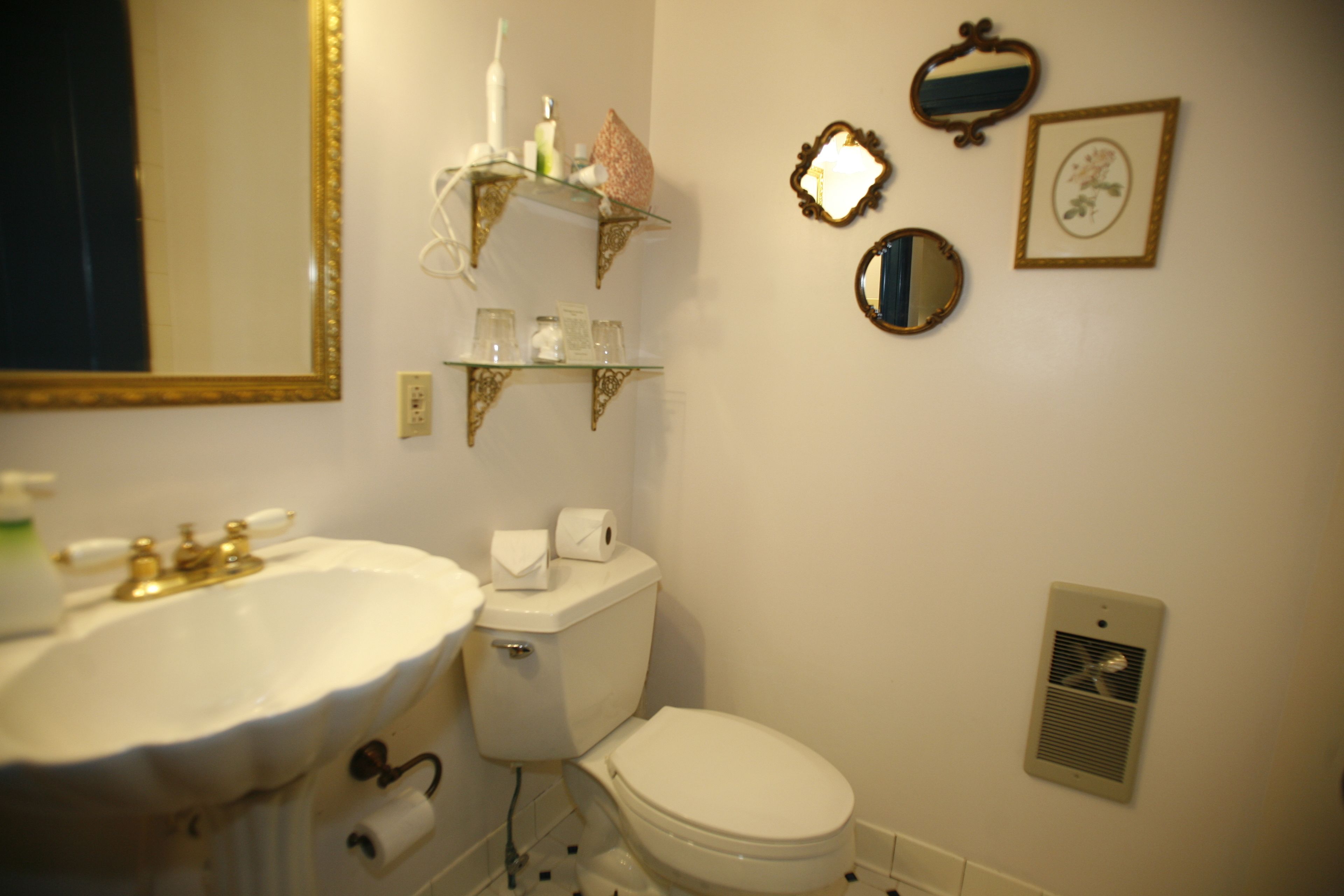 Une salle de bain avec un lavabo blanc, des toilettes et des miroirs décoratifs.