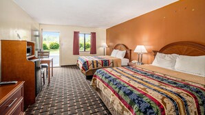 Quarto de hotel com duas camas, uma escrivaninha e vista para o verde lá fora.