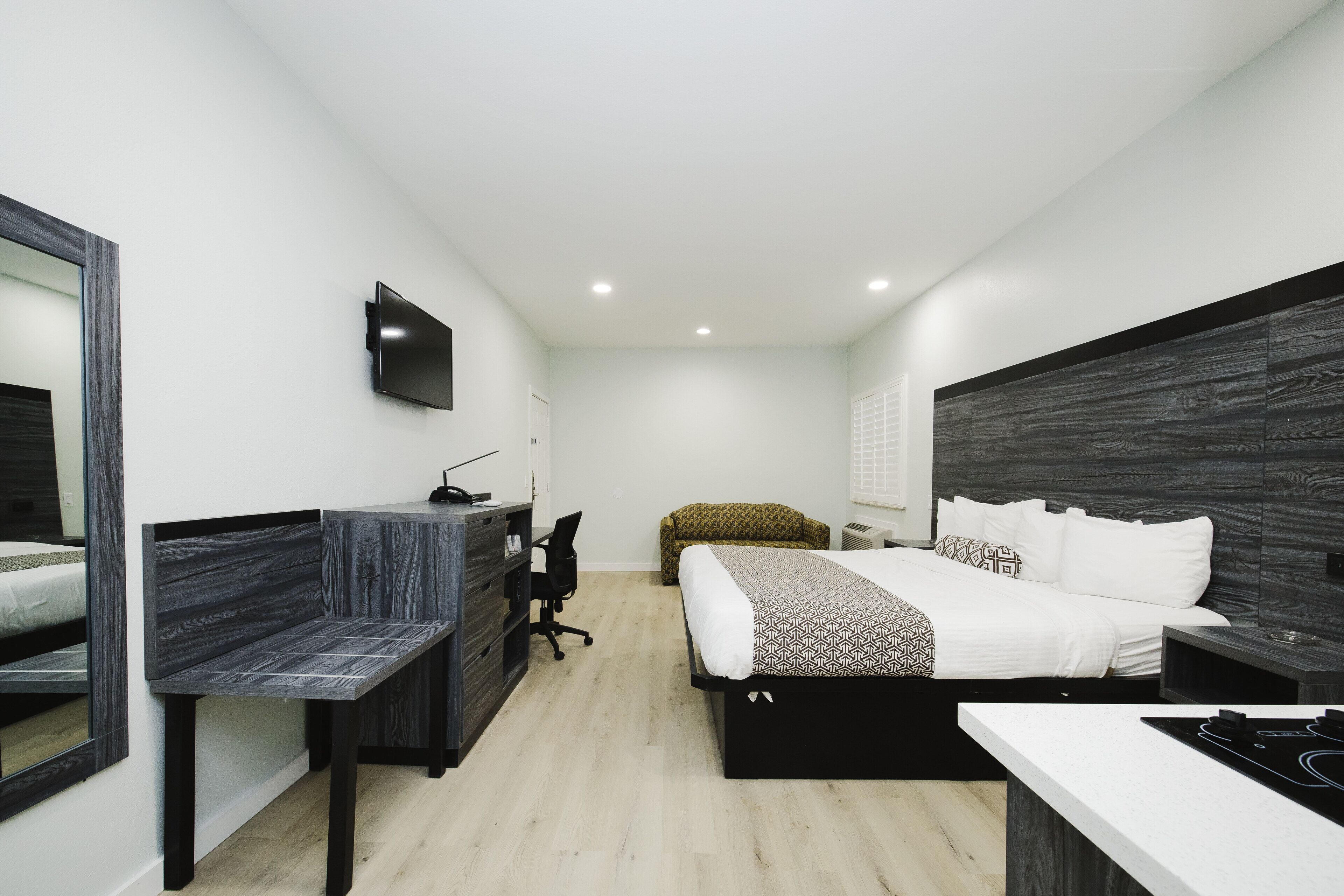 Un dormitorio moderno con cama, escritorio, silla y televisor montado en la pared.