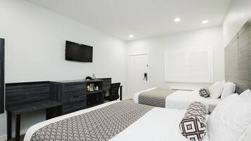 A modern hotel room with a large bed, a desk, and a TV mounted on the wall.