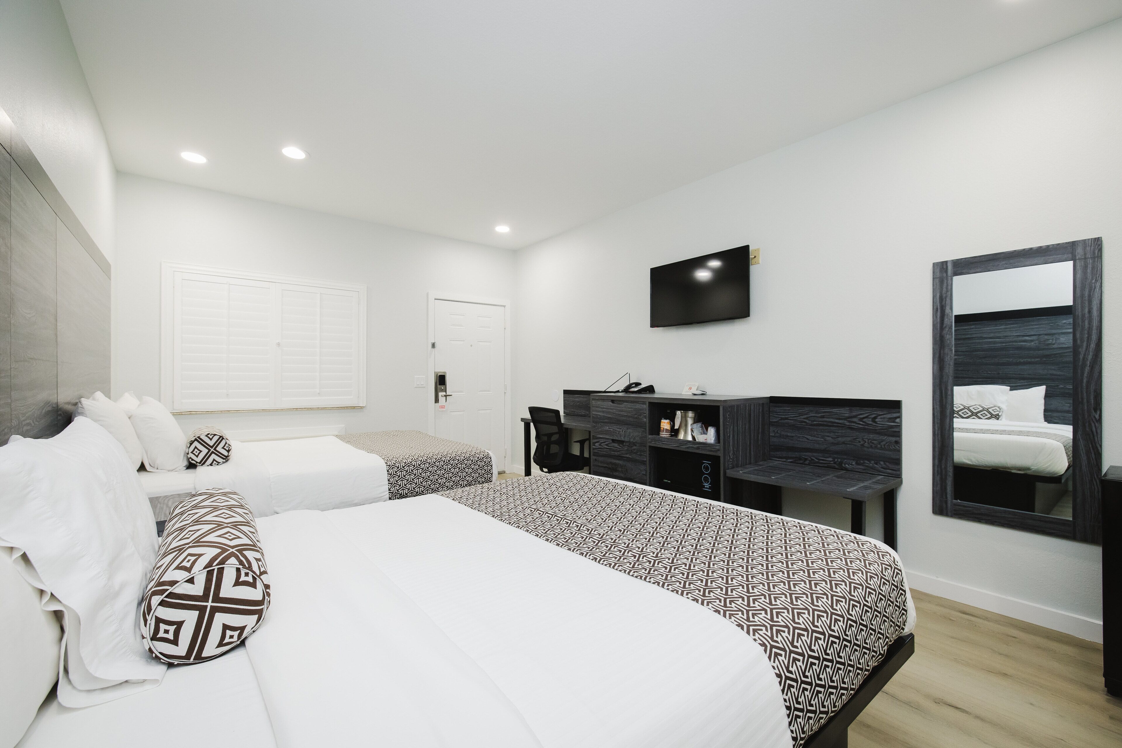 Une chambre d’hôtel moderne équipée de deux lits, d’un bureau, d’une télévision et d’un miroir.