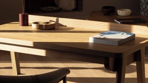 Een houten tafel met een boek, een lamp en een vaas.