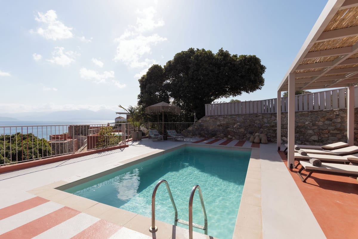 Ein Pool mit Meerblick, Liegestühle und eine Pergola.