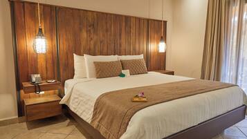A hotel room with a wooden headboard, a bed with white bedding and brown accents, a bedside table with a phone, and a nightstand.