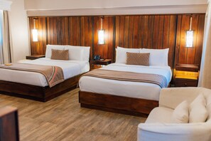 Une chambre d’hôtel avec deux lits, des têtes de lit en bois, des lampes de chevet et un plancher en bois.