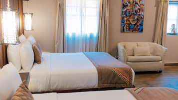 Habitación de hotel con una cama grande, un sofá, un cuadro en la pared y una ventana con cortinas.