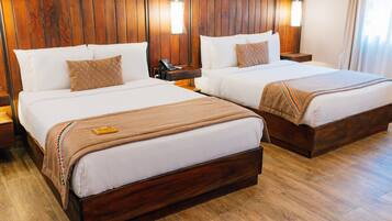Habitación de hotel con dos camas, cabeceros de madera, mesitas de noche y un teléfono.