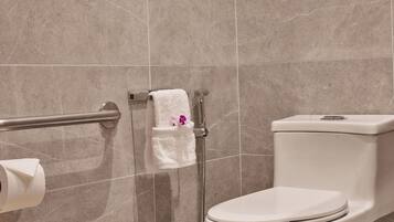 A bathroom with a toilet, a handrail, and a towel rack.