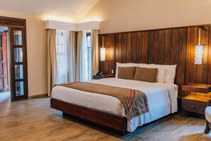 Een hotelkamer met een groot bed, houten lambrisering, een nachtkastje en een bedlampje.