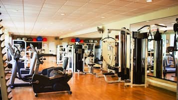 A gym with various exercise equipment, including treadmills, weight machines, and a rowing machine.