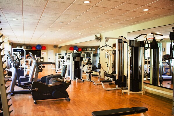 A gym with various exercise equipment, including treadmills, weight machines, and a rowing machine.