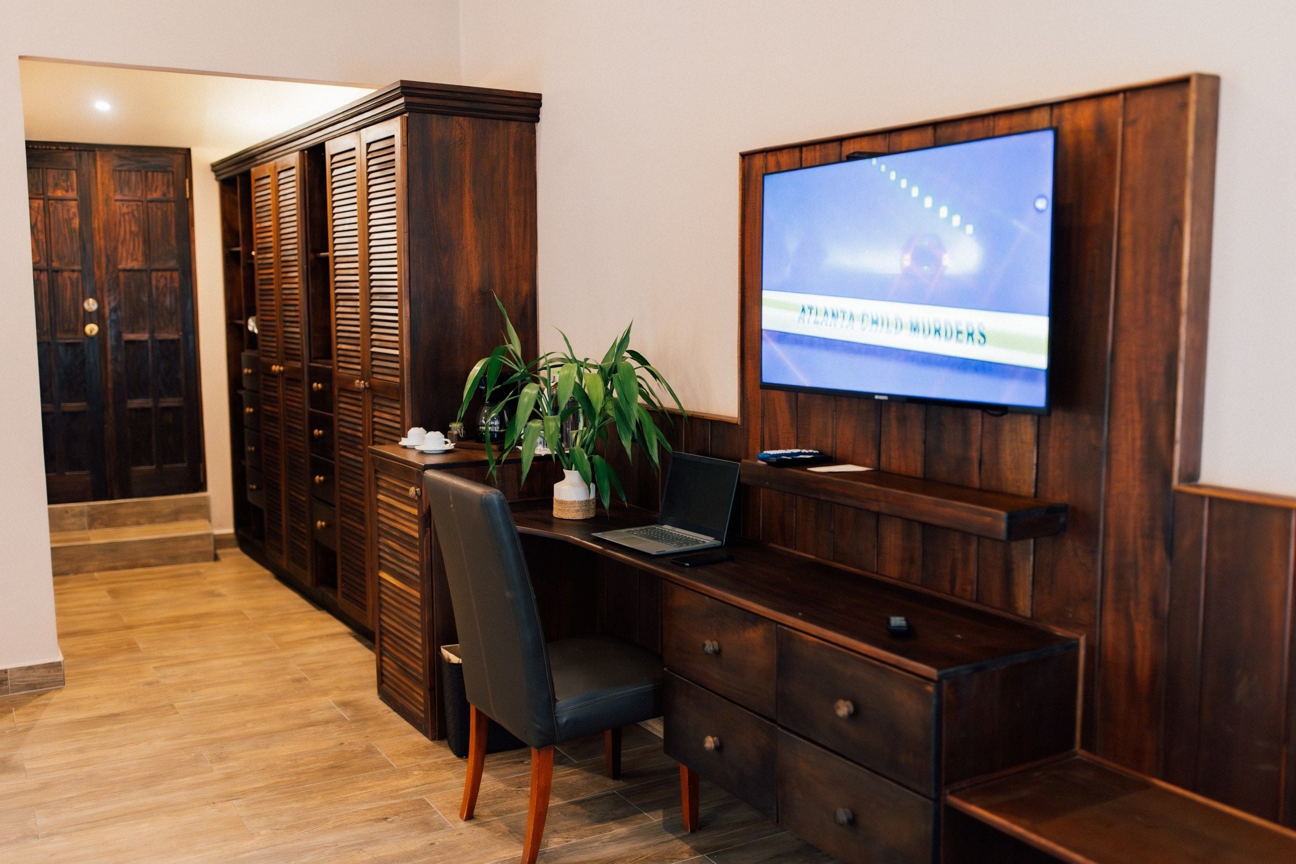 Una habitación de hotel con escritorio, silla, televisor y armario.