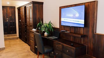 Una habitación de hotel con escritorio, silla, televisor y armario.