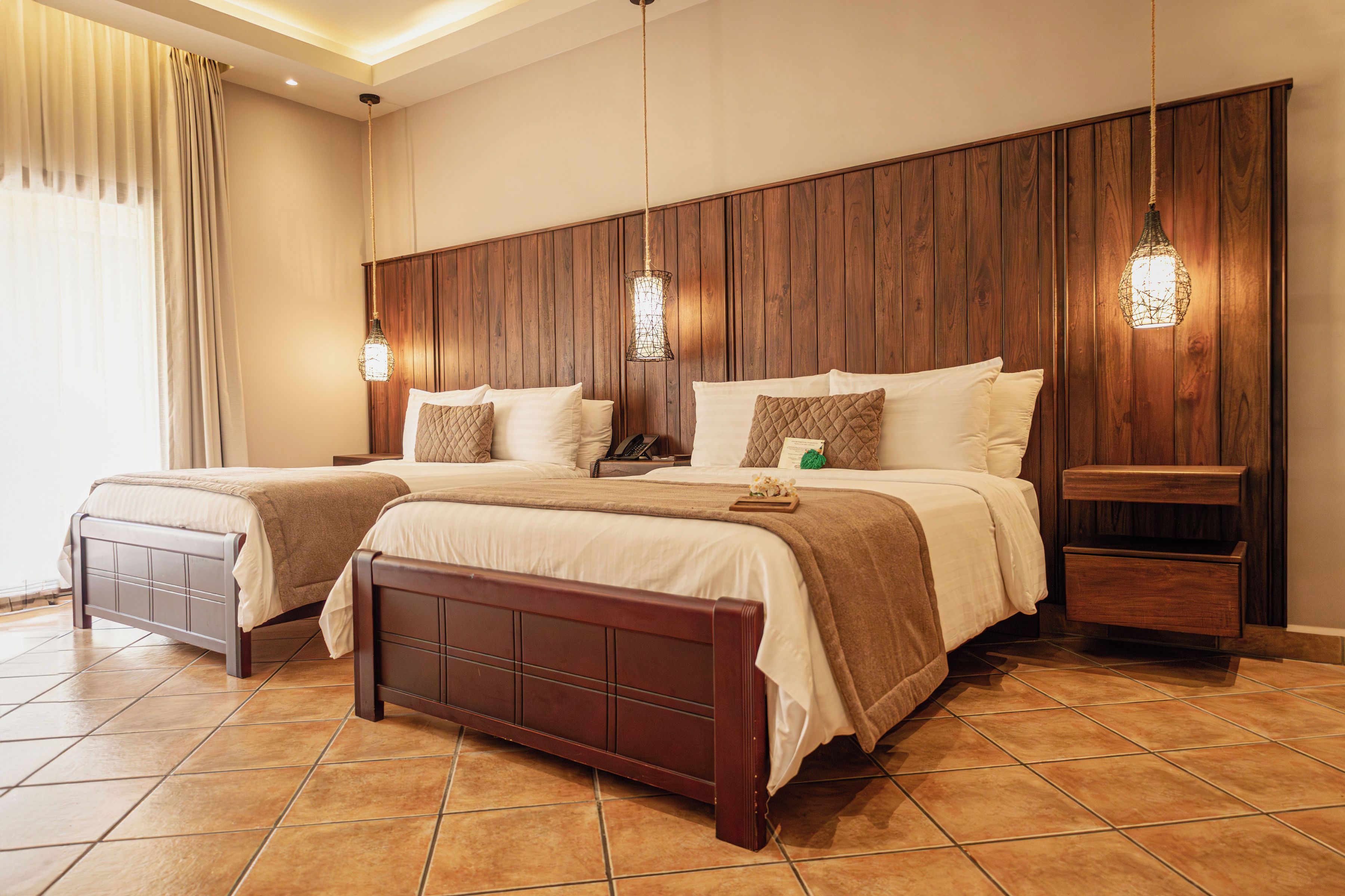 A hotel room with a large bed, two bedside tables, a nightstand, and a wooden headboard.