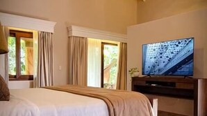 Een slaapkamer met een bed, een televisie, een plafondventilator en een raam.