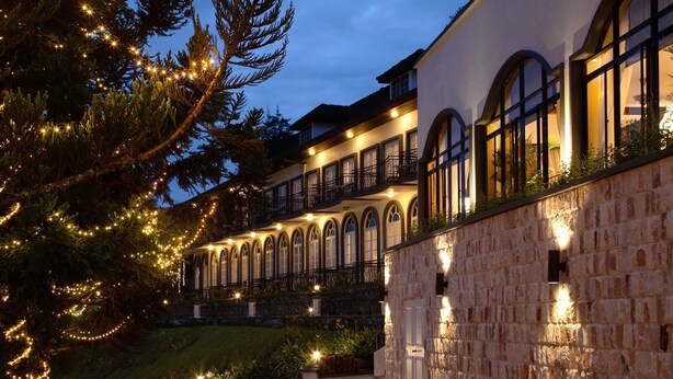 A multi-story building with arched windows and balconies, surrounded by stone walls and greenery. - Cameron Highlands Resort (Tanah Rata)