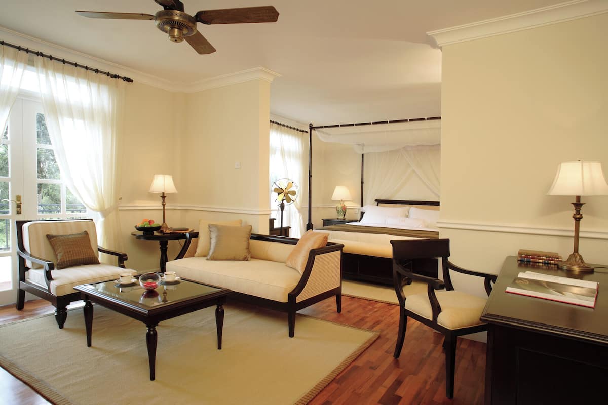 A well-lit living room with a sofa, chairs, a coffee table, and a desk with a lamp.