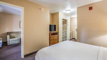 A hotel room with a bed, a TV on a wooden dresser, a closet, and a door leading to another room.