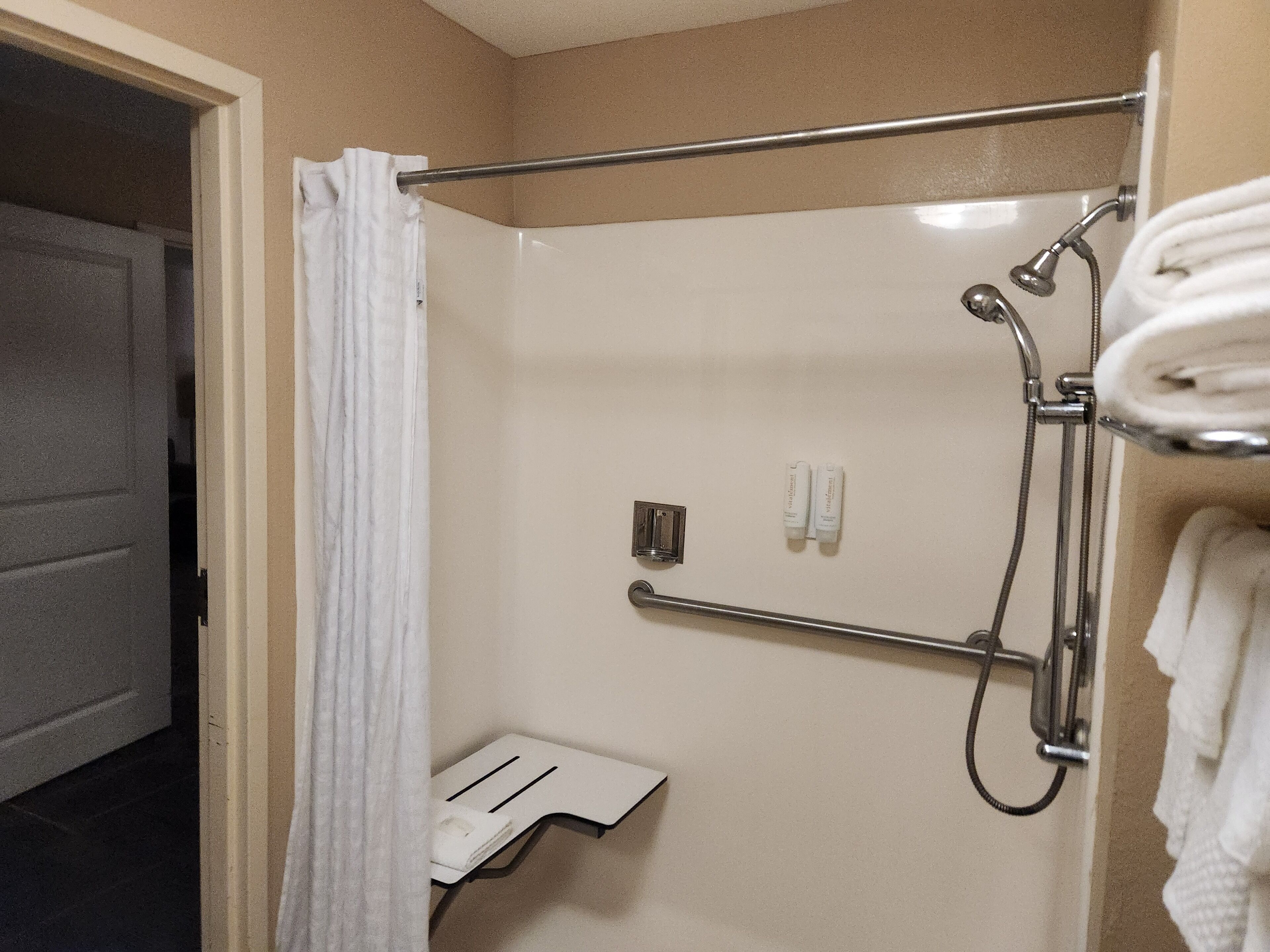 A shower area with a glass door, a towel rack, and a small shelf.