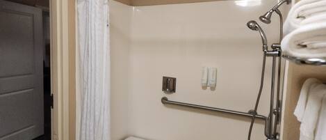 Un espace douche doté d’une porte en verre, d’un porte-serviettes et d’une petite étagère.