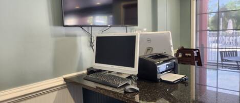Ein Schreibtisch mit einem Desktop-Computer, einem Drucker und einem Papierkorb.