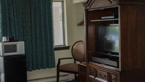 Ein Zimmer mit einem Holzkasten, der einen Fernseher, eine Mikrowelle und einen Sessel beherbergt.