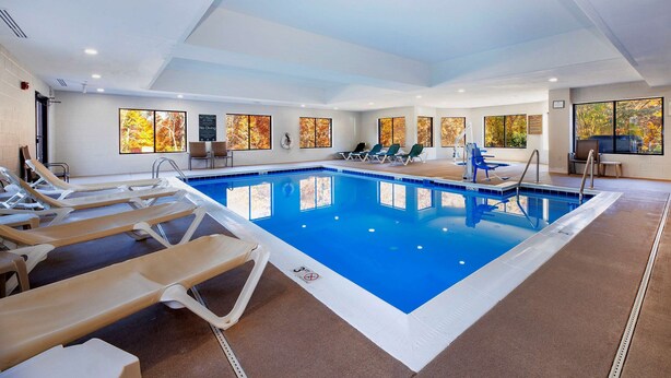 Una piscina con tumbonas, una escalera y cuadros en las paredes.