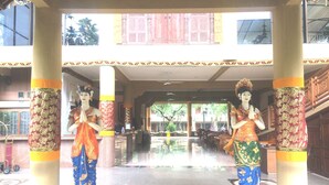 A building entrance with two statues of deities, a covered walkway, and a view of the surrounding area. - Melasti Beach Resort & Spa (Legian)