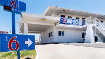 Un motel con un letrero con el número '6', un cartel de 'ABIERTO' y una señal de flecha direccional.