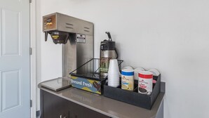 A coffee station with a coffee machine, cups, and containers of creamer and sugar. - Motel 6 Barstow, CA - Route 66 (Barstow)