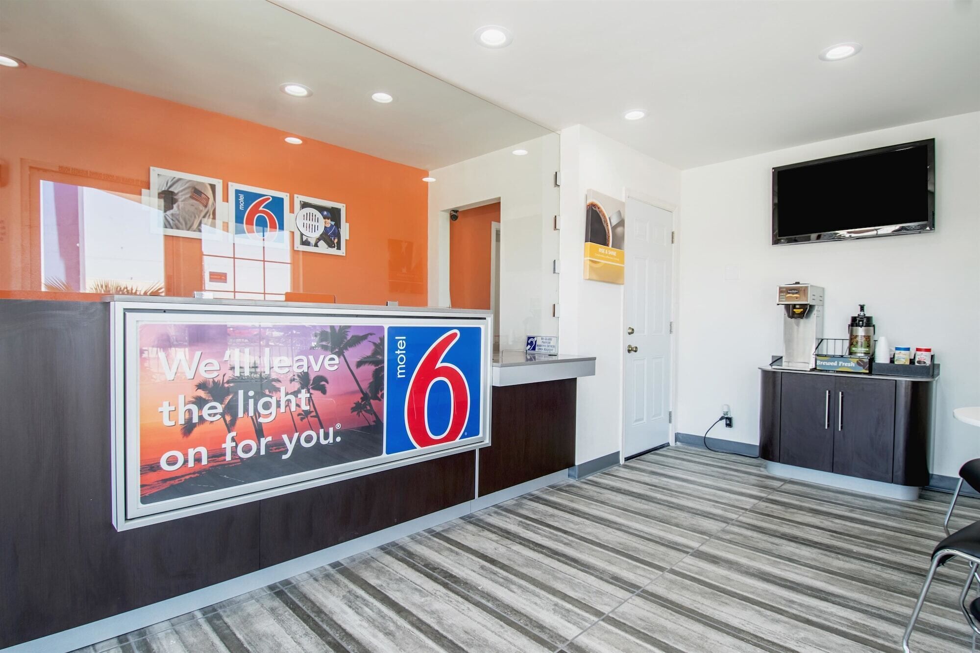 A hotel reception area with a large sign reading "We'll leave the light on for you."