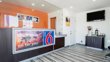 A hotel reception area with a large sign reading "We'll leave the light on for you."