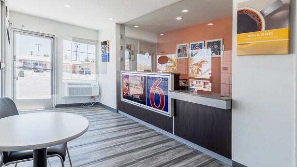 A hotel reception area with a counter, a seating area, and a view of the street outside. - Motel 6 Barstow, CA - Route 66 (Barstow)