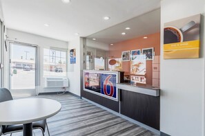 A hotel reception area with a counter, a seating area, and a view of the street outside.