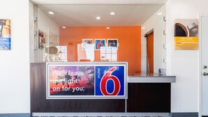 A motel reception desk with a large sign reading "We'll leave the light on for you." - Motel 6 Barstow, CA - Route 66 (Barstow)