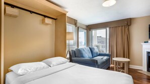 A hotel room with a bed, a blue sofa, a small table, and a fireplace. - Bluegreen Vacations The Breakers Resort, an Ascend Collection Resort (Dennis Port)