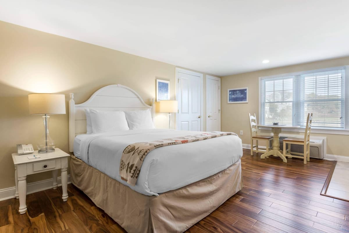 A bedroom with a bed, bedside tables, a desk, and a chair.