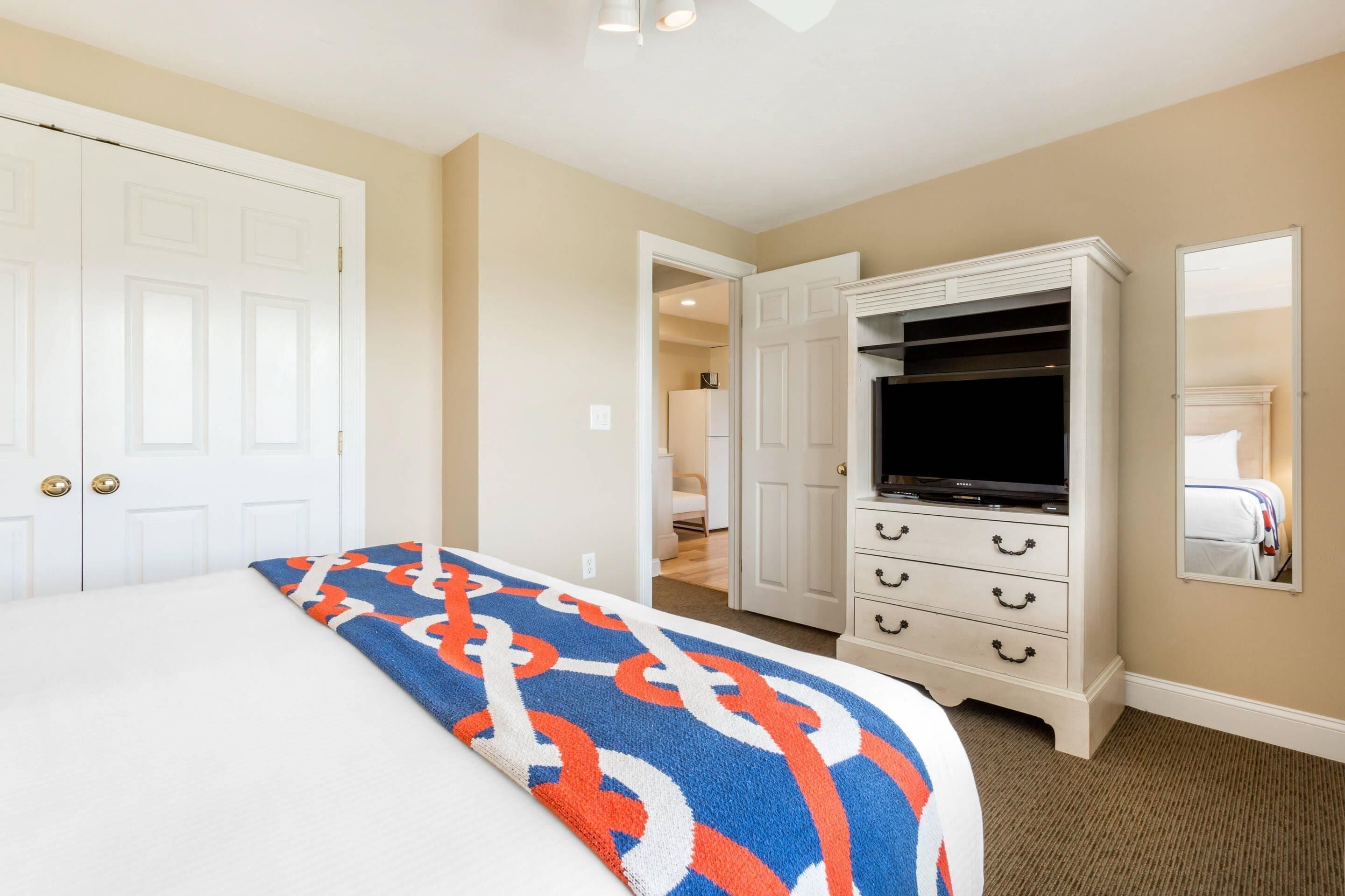 A hotel room with a bed, a TV, a wardrobe, and a mirror.