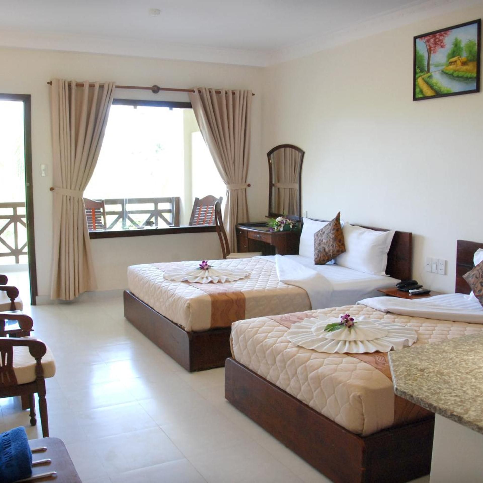 A hotel room with two beds, a desk, and a chair.