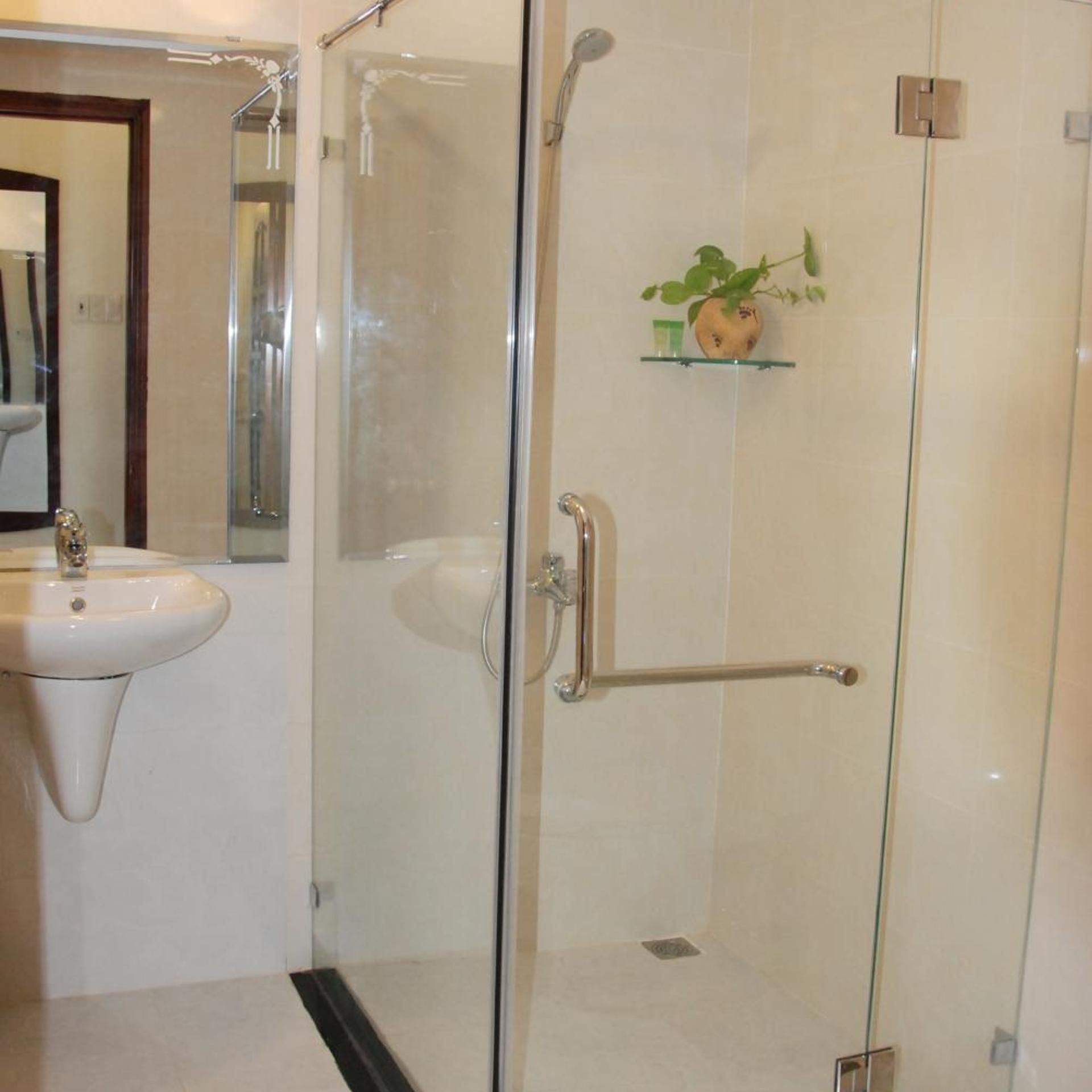 A bathroom with a glass-enclosed shower, a sink, and a small shelf with toiletries.