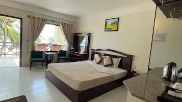 A hotel room with a bed, a desk, a chair, a window with curtains, and a view of the outdoors.