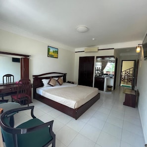 A hotel room with a bed, a desk, a chair, a dining table, and a kitchen area. - Ocean Star Resort (Phan Thiet)