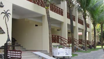 A building with multiple floors, a staircase leading to the entrance, and palm trees surrounding the area.